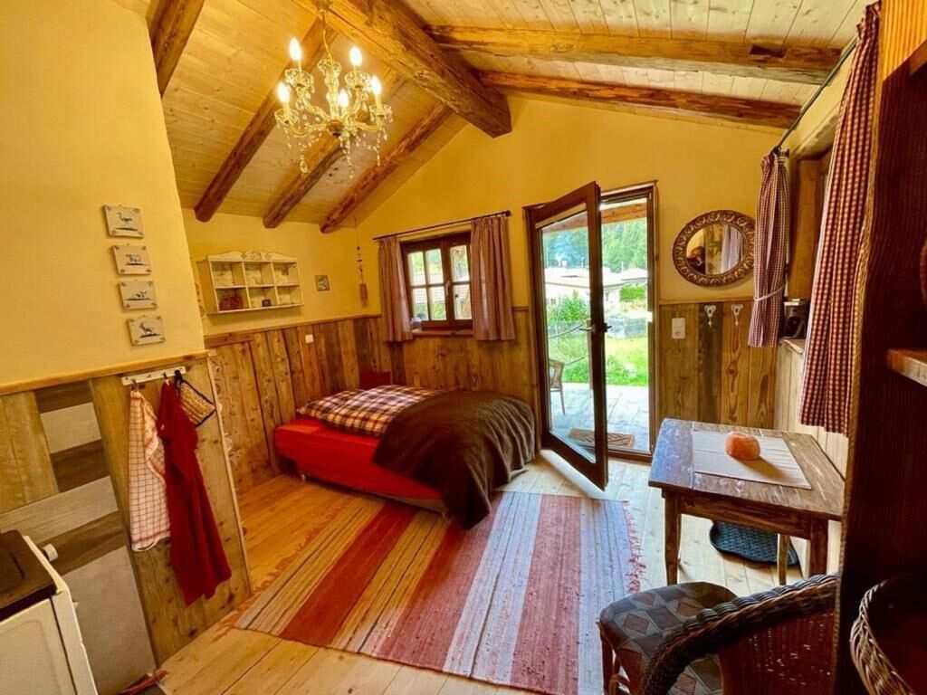 Une pièce confortable avec un lit, une table, un lustre et une vue sur l’extérieur.