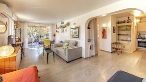 Ein geräumiger Wohnbereich mit einer Couch, einem Esstisch und einer Küchenzeile mit Mikrowelle und Backofen.
