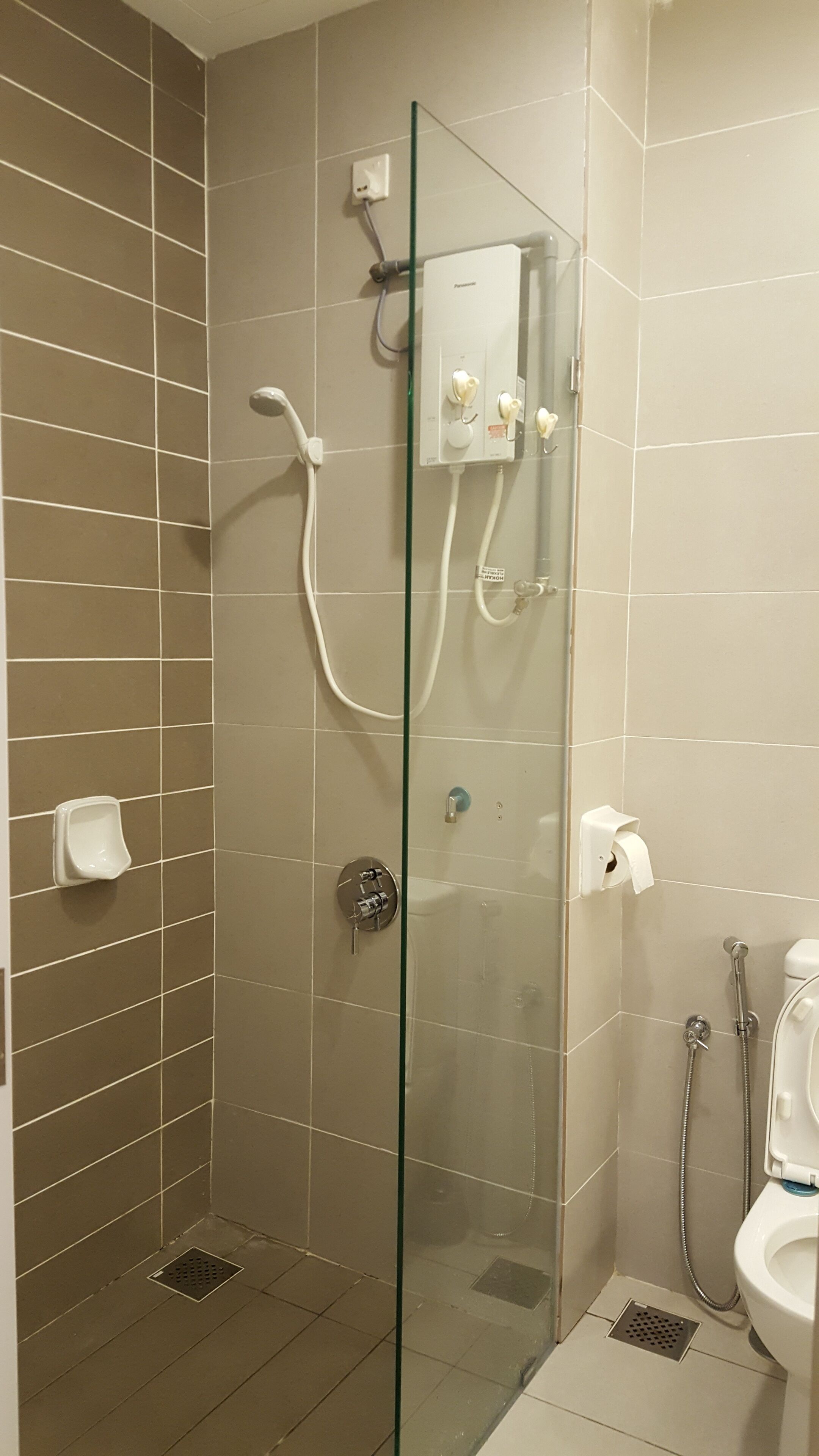 A modern bathroom with a glass-enclosed shower, a toilet, and a urinal.