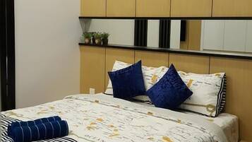 Quarto com cama, almofadas, mesa de cabeceira e prateleira com plantas.