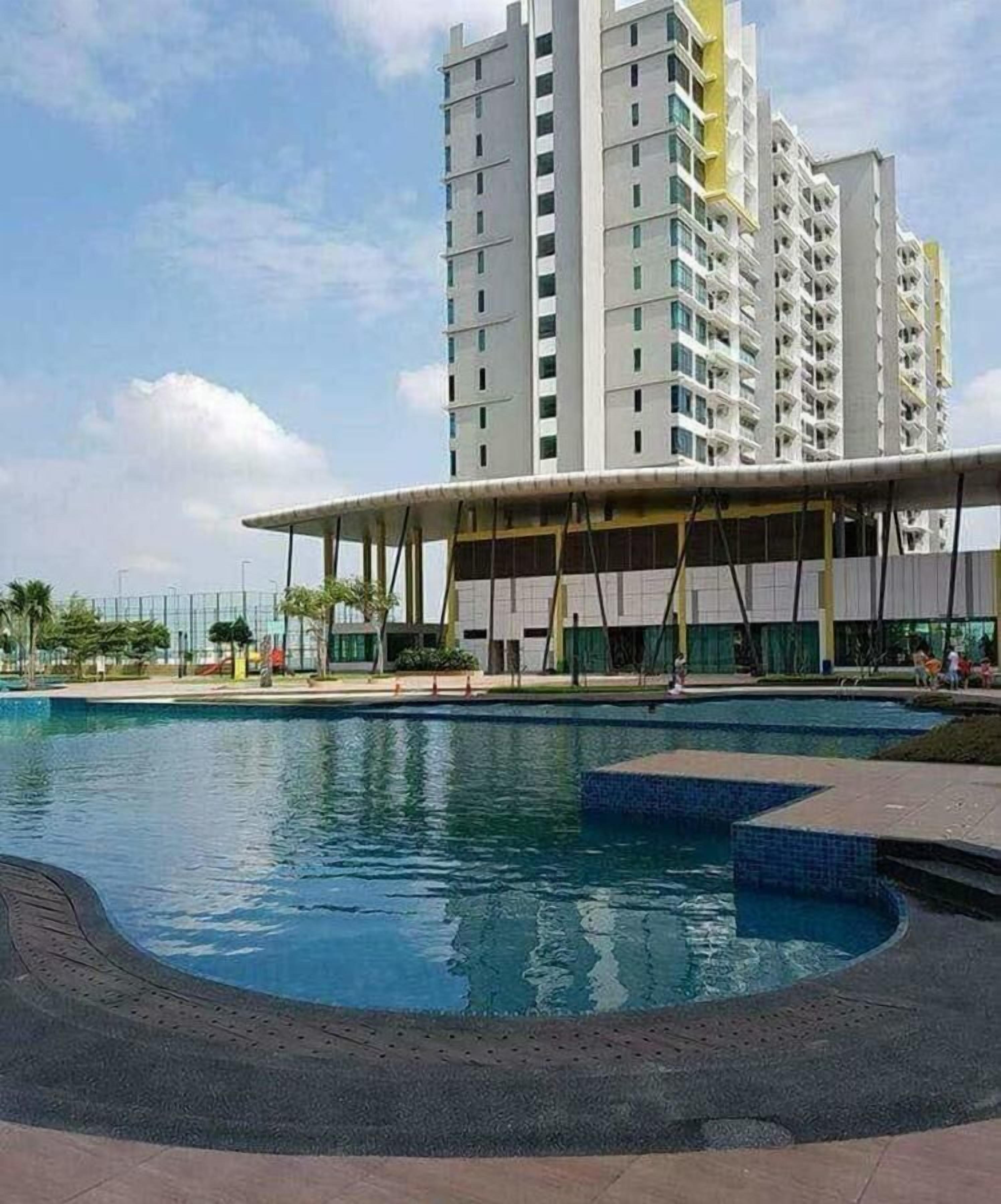Un hotel moderno con zona de piscina, un pabellón cubierto y un edificio alto al fondo.
