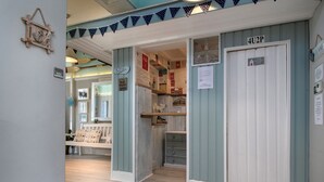 A hallway with a wooden bench, a door labeled "4U2P", and a wall decorated with various signs and items. - Beachside Guest House (Llandudno)
