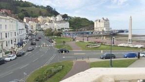 A coastal town with a prominent hotel, a monument, and a busy street. - Beachside Guest House (Llandudno)