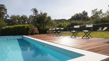 Ein Schwimmbecken mit Holzterrasse und Liegestühlen.