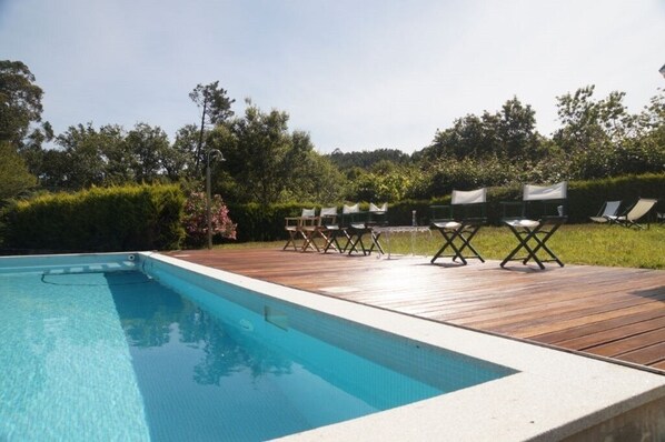 Une piscine avec une terrasse en bois et des chaises longues.