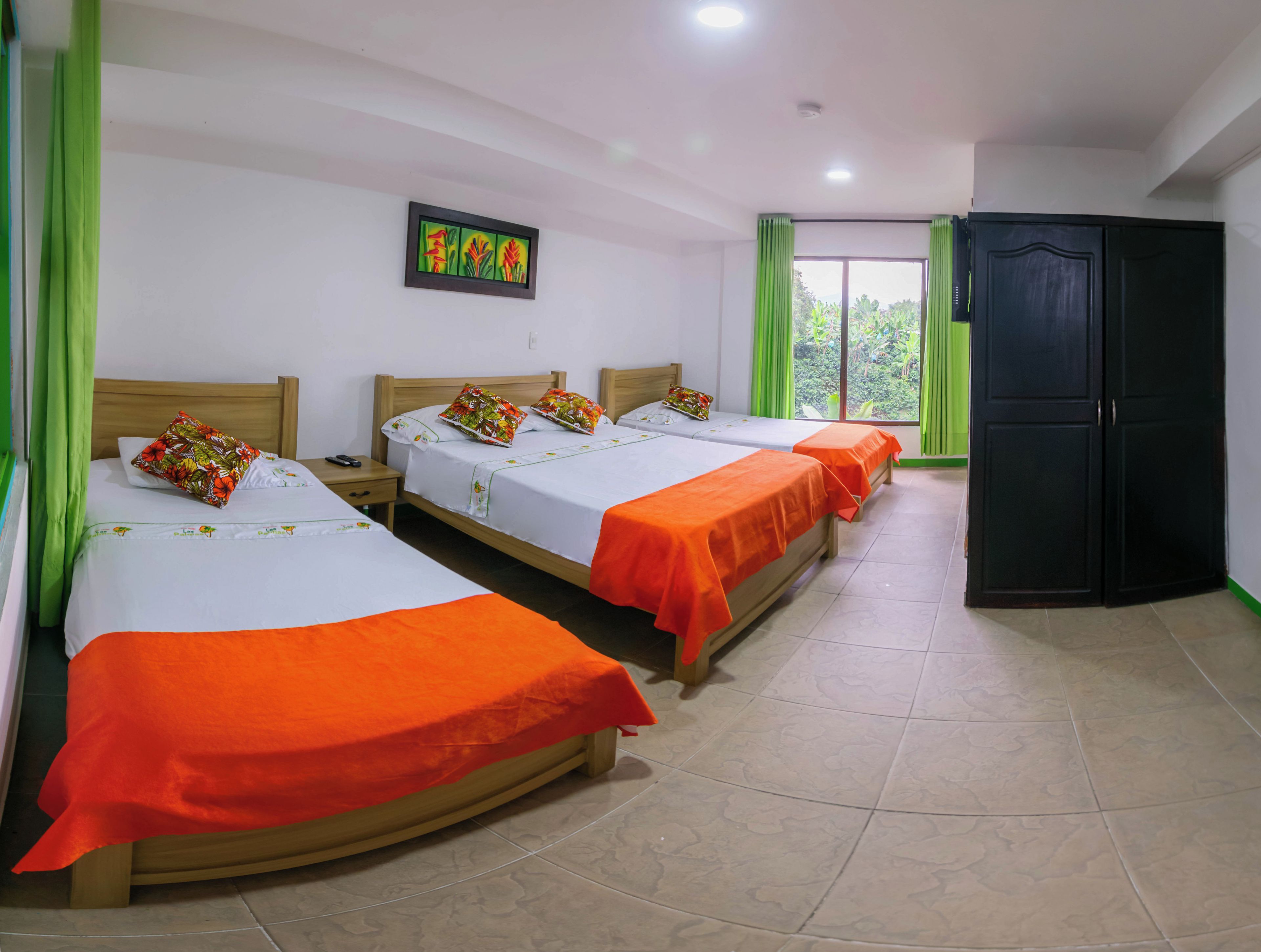 Habitación de hotel con tres camas, un armario y una ventana con cortinas.