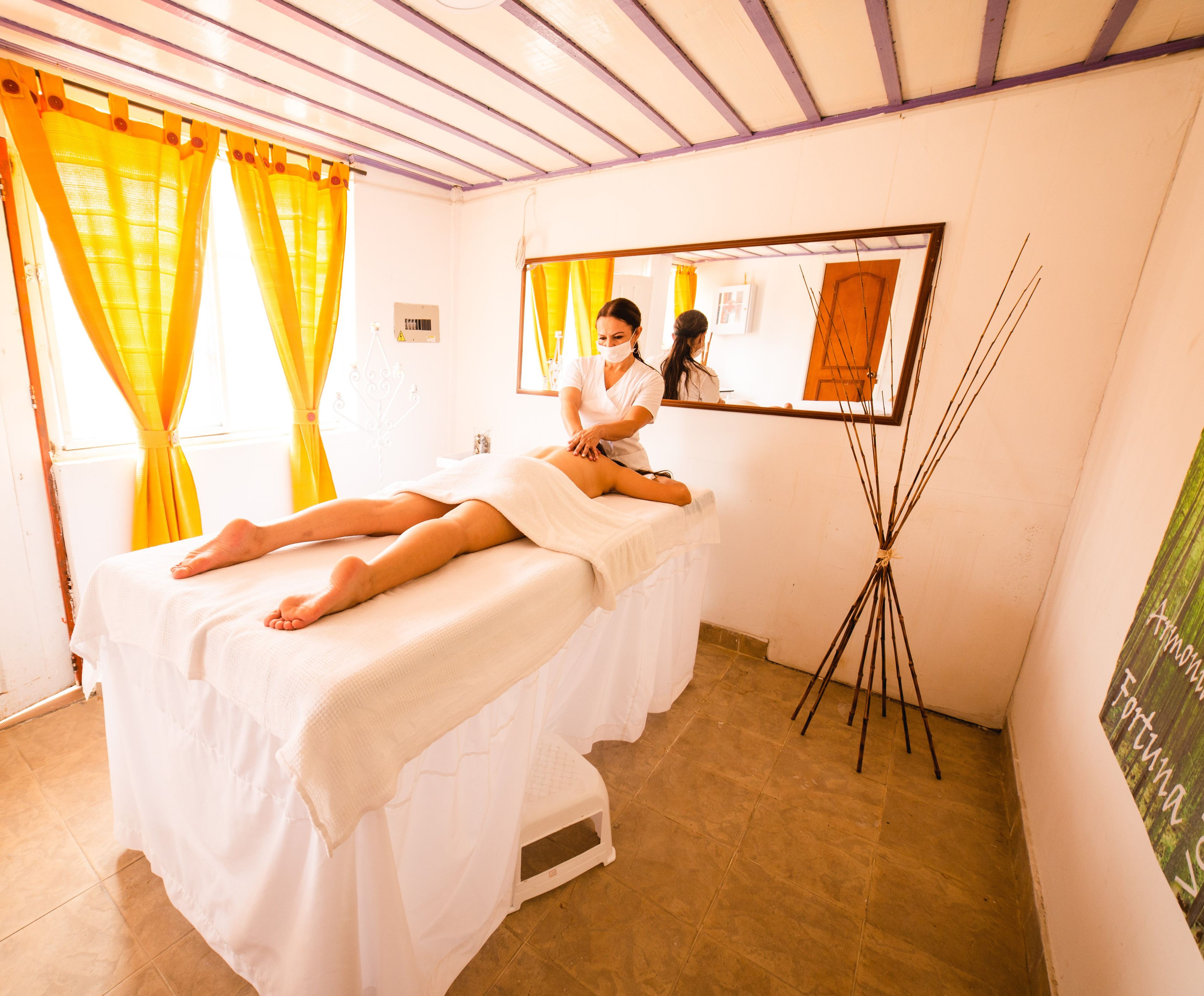A room with a massage table, a mirror, and a tripod with sticks.