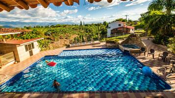 Relax by the serene pool surrounded by lush greenery and distant mountains.
