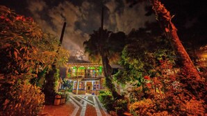 A brightly lit building with a balcony, surrounded by trees and plants. - Eco Hotel Las Palmas (Armenia)