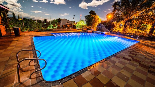 A swimming pool with a checkered tile pattern, a metal pool ladder, and a view of the sky with clouds. - Eco Hotel Las Palmas (Armenia)