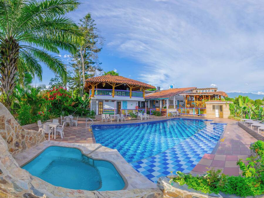 A resort with a swimming pool, outdoor seating, and a view of the mountains.