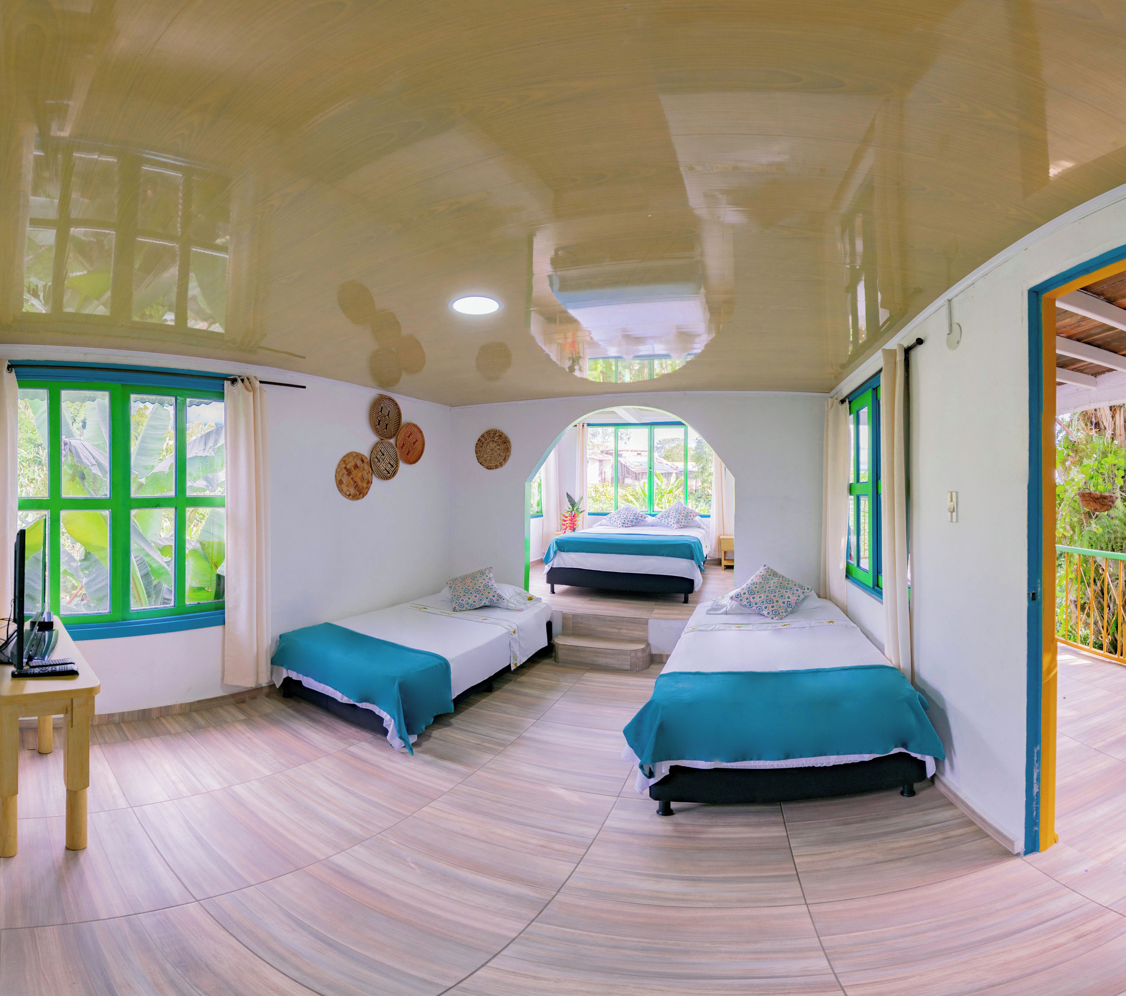 A room with two beds, a desk, and a window with curtains.