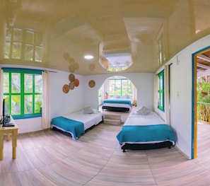 Ein Zimmer mit zwei Betten, einem Schreibtisch und einem Fenster mit Vorhängen.