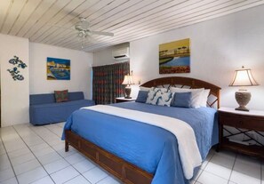 Une chambre à coucher avec un grand lit, une table de chevet, une lampe et une fenêtre avec des rideaux.