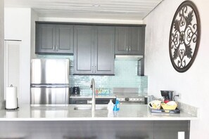 Une cuisine moderne dotée d’appareils électroménagers en acier inoxydable, de meubles de couleur grise et d’un élément décoratif mural.