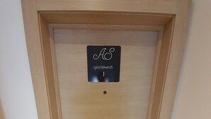 A wooden door with a sign above it reading "AS apartments" and a welcome mat at the entrance.