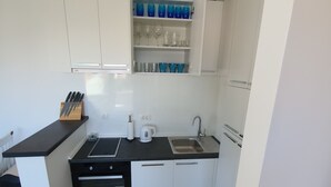 Et moderne køkken med hvide skabe, en sort bordplade og en indbygget ovn.