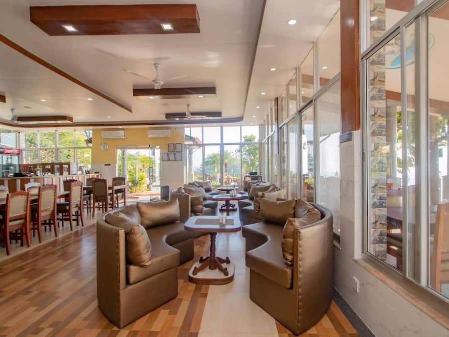 A spacious indoor area with leather sofas, wooden tables, and a bar area with a Coca-Cola refrigerator.