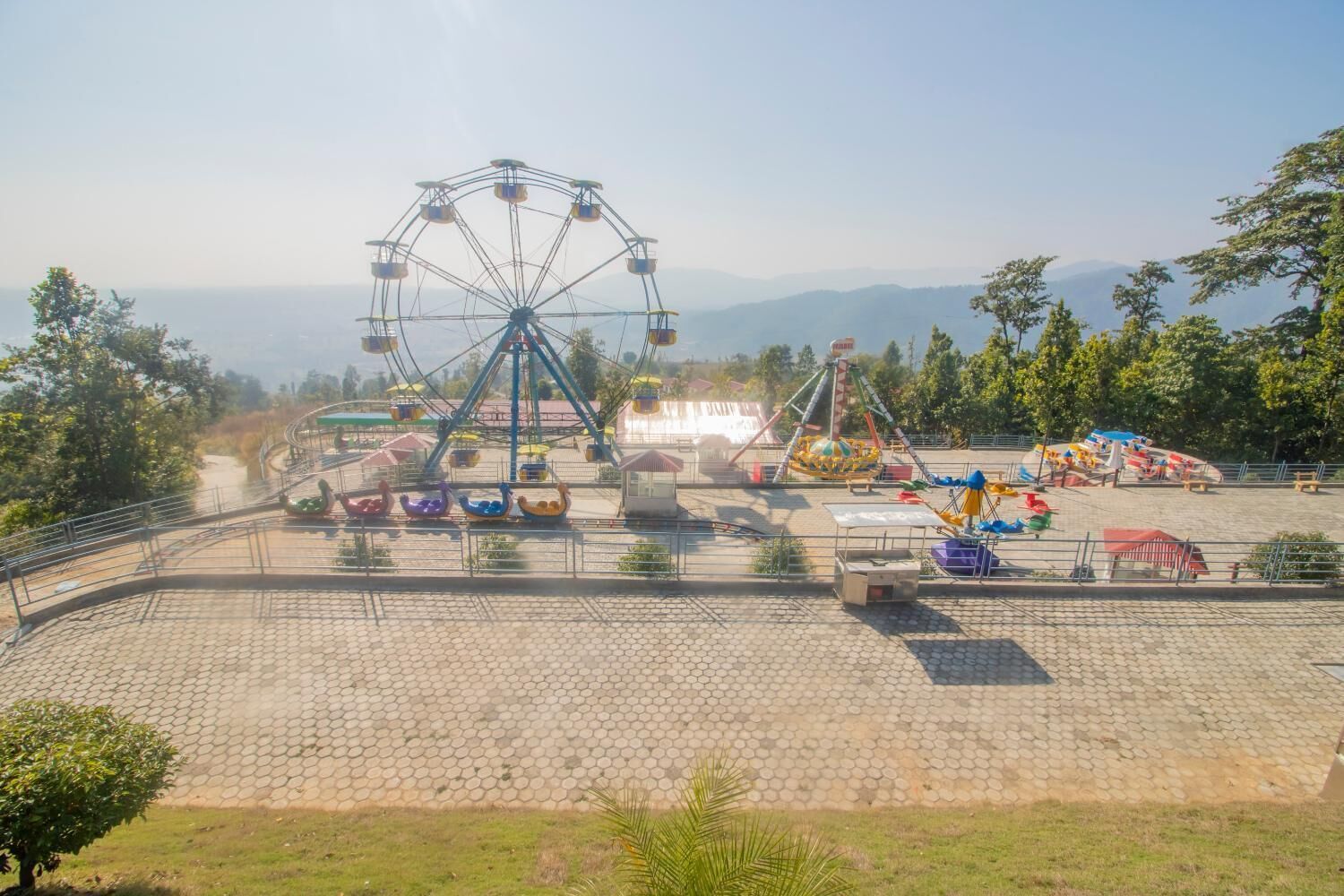 A Ferris wheel and various amusement rides at an outdoor amusement park.