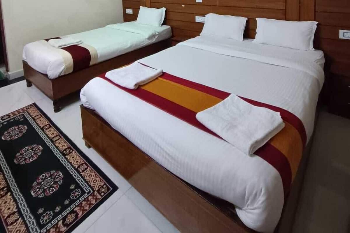 A hotel room with two beds, a wooden headboard, a patterned rug, and a ceiling with a hexagonal design.