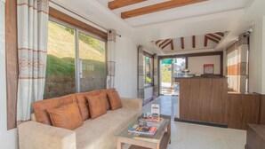 A modern living room with a sofa, coffee table, and a view of a garden through large windows. - Kabilas Resort and Funpark (Kabilas)
