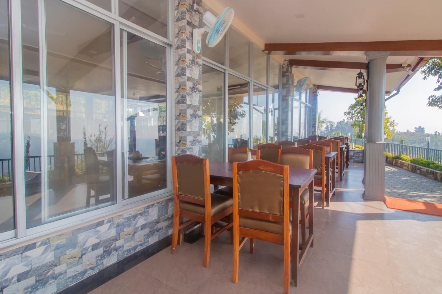 A restaurant with outdoor seating, stone walls, and large windows.