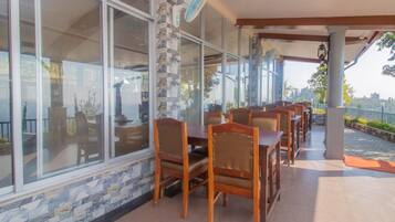 A restaurant with outdoor seating, stone walls, and large windows.