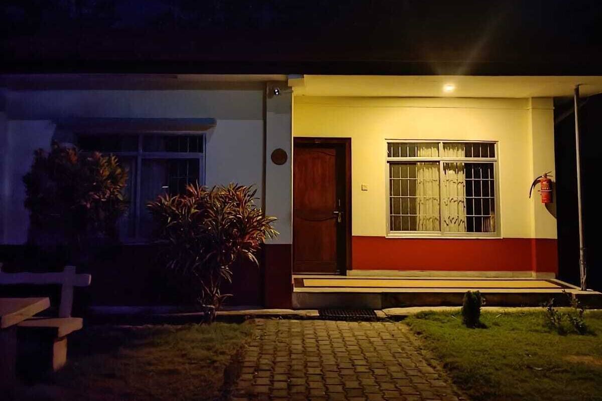 A house with a red and white exterior, a front door, and a window with curtains.