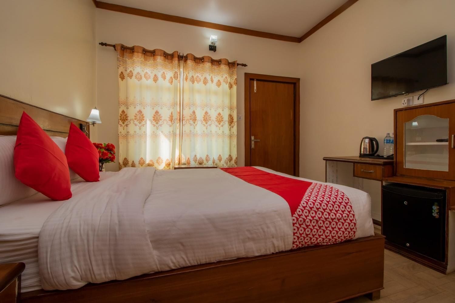 A hotel room with a bed, a desk, a television, and a wardrobe.