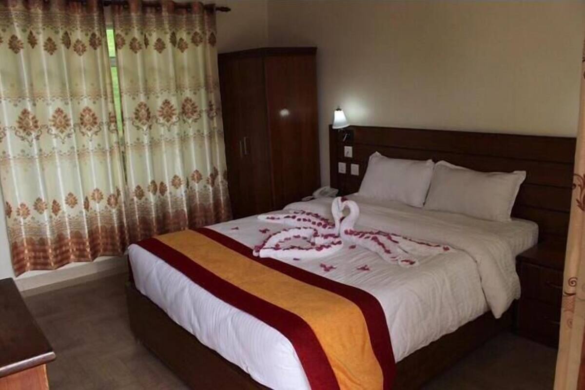 A hotel room with a bed, a wardrobe, a bedside table, and a lamp.