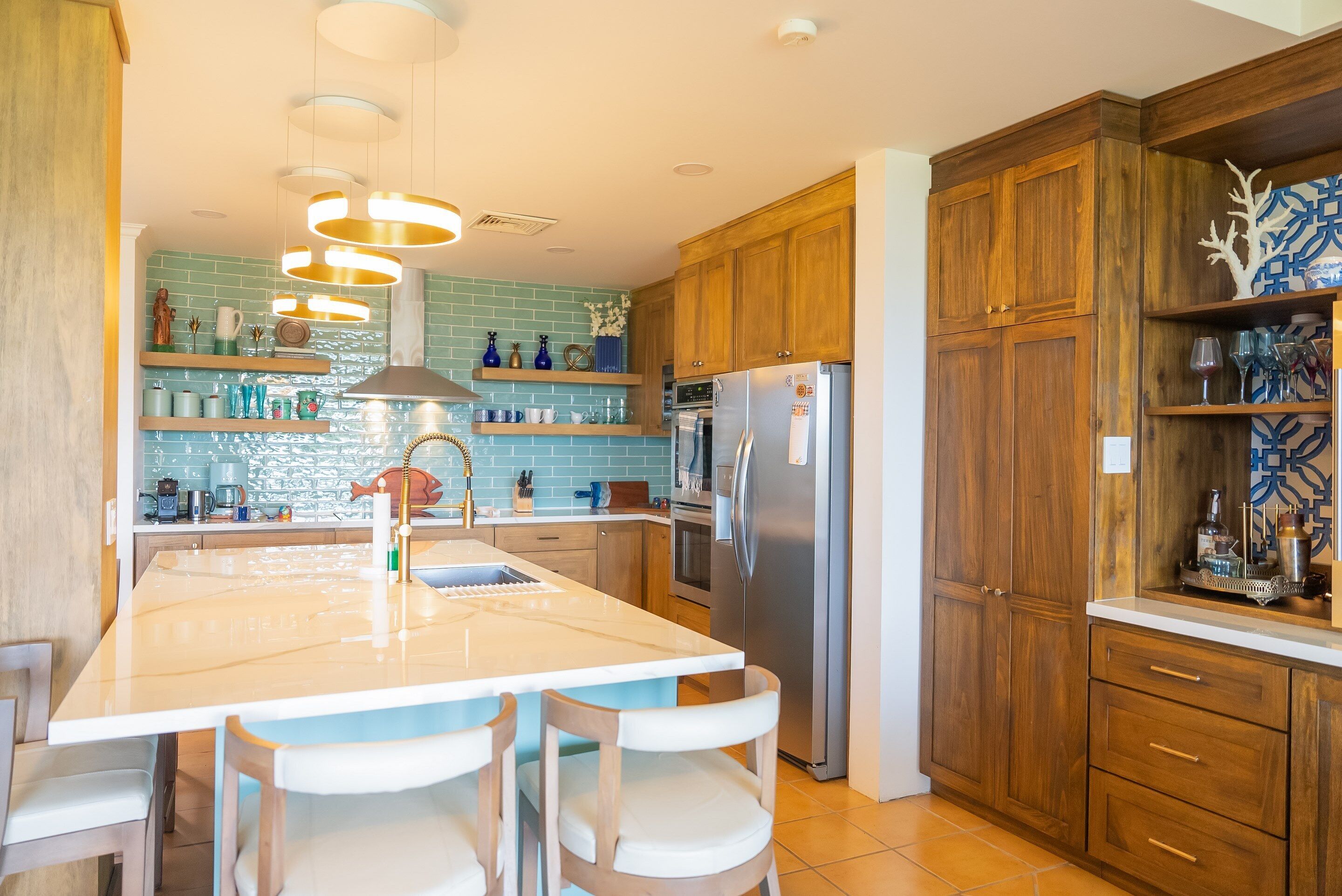 A kitchen with wooden cabinets, a stainless steel refrigerator, and a central island with chairs.