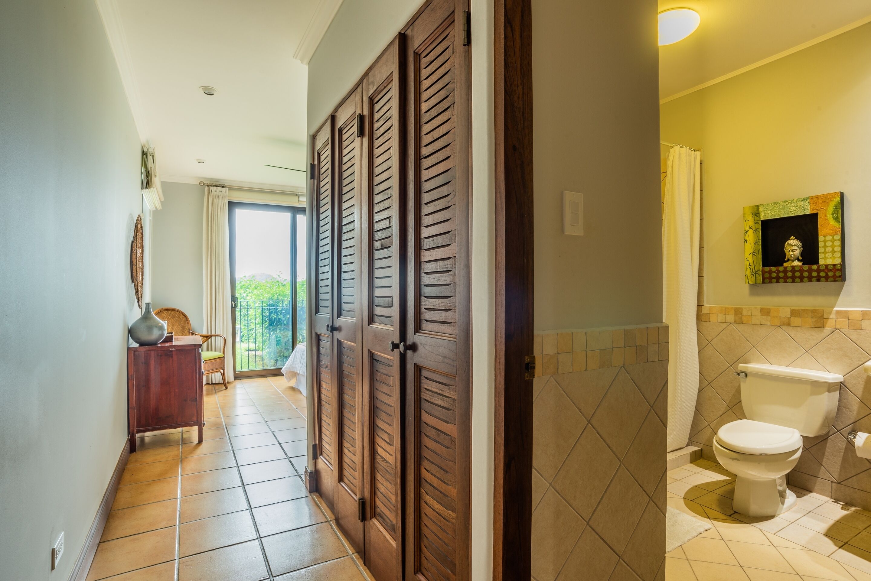 A hallway leading to a bathroom with a toilet, a sink, and a shower curtain.