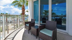 A balcony with wicker furniture and a view of the beach and palm trees. - 2-bedroom resort condo w/private balcony & amenities! 🌴 (Destin)