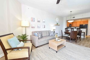 Una sala de estar con sofá, sillón, mesa de centro y comedor con sillas y una mesa.