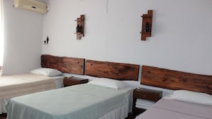Habitación de hotel con dos camas individuales, cabeceros de madera, mesitas de noche y estantes en la pared.