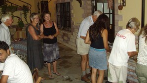 Un grupo de personas reunidas en un espacio al aire libre con un muro de ladrillo y una pérgola de madera.