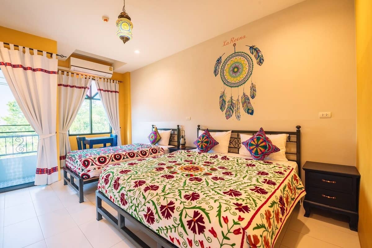 A bedroom with a large bed, a nightstand, a window with curtains, and a wall decoration.