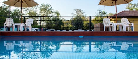 Una piscina al aire libre, sombrillas, sillones reclinables de piscina