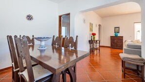 A dining area with a wooden table and chairs, a decorative bowl, and a tiled floor. - Casa Giovanna Praia da Luz 3 bedrooms, aircon, solar heated pool & sea view. (Luz)