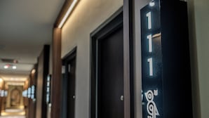Corredor de hotel com portas numeradas 111, apresentando design moderno e um logotipo na parte inferior.