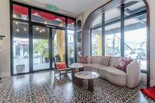 Um interior moderno com uma parede de vidro curva, um sofá com almofadas estampadas e um chão em mosaico.