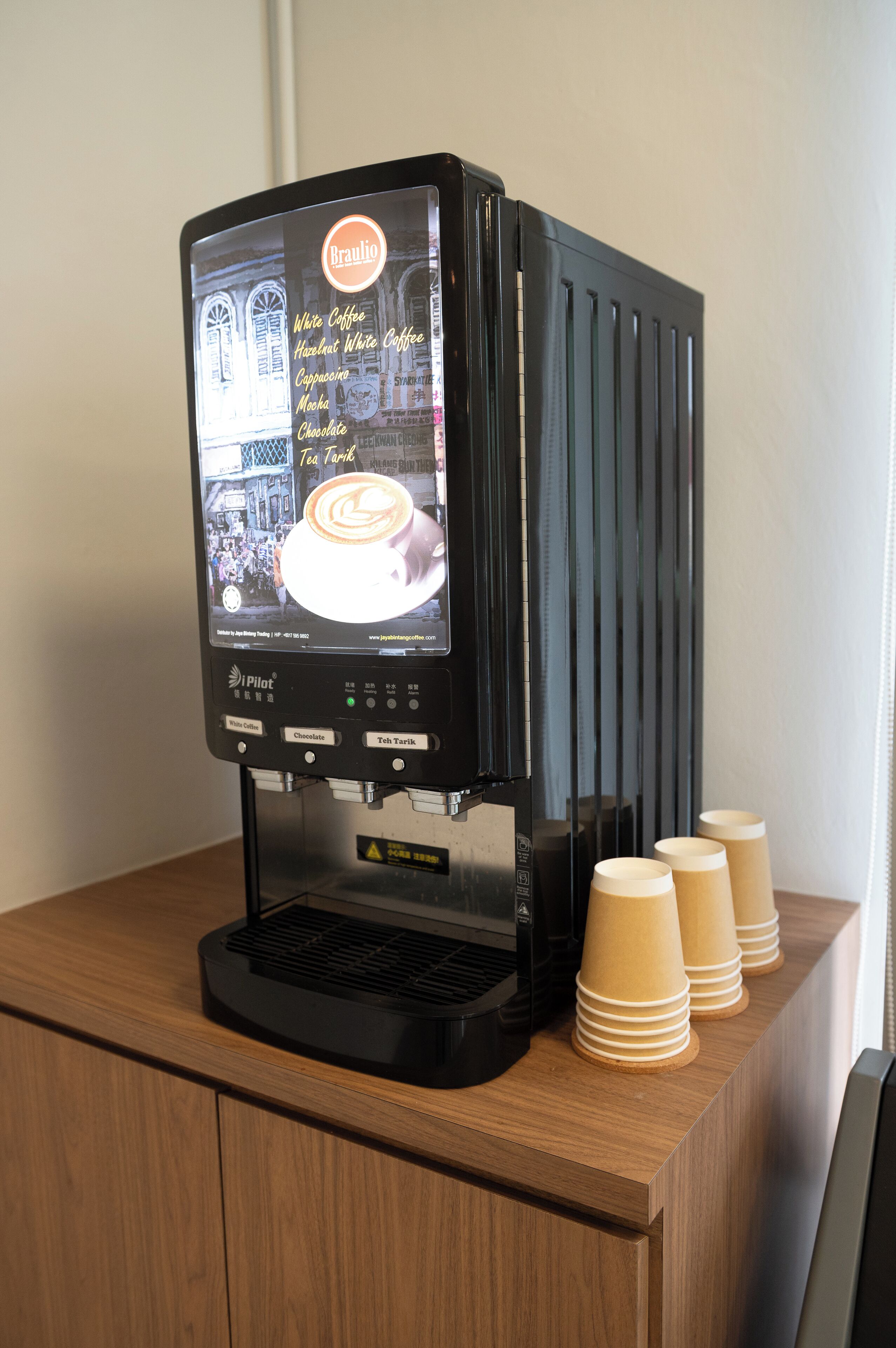 A coffee machine with a digital display and options for white coffee, hazelnut white coffee, cappuccino, mocha, chocolate, and tea.