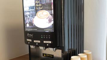 A coffee machine with a digital display and options for white coffee, hazelnut white coffee, cappuccino, mocha, chocolate, and tea.