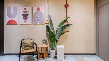 A modern room with a minimalist design, featuring a chair, a small table, a potted plant, and a white device on the floor.