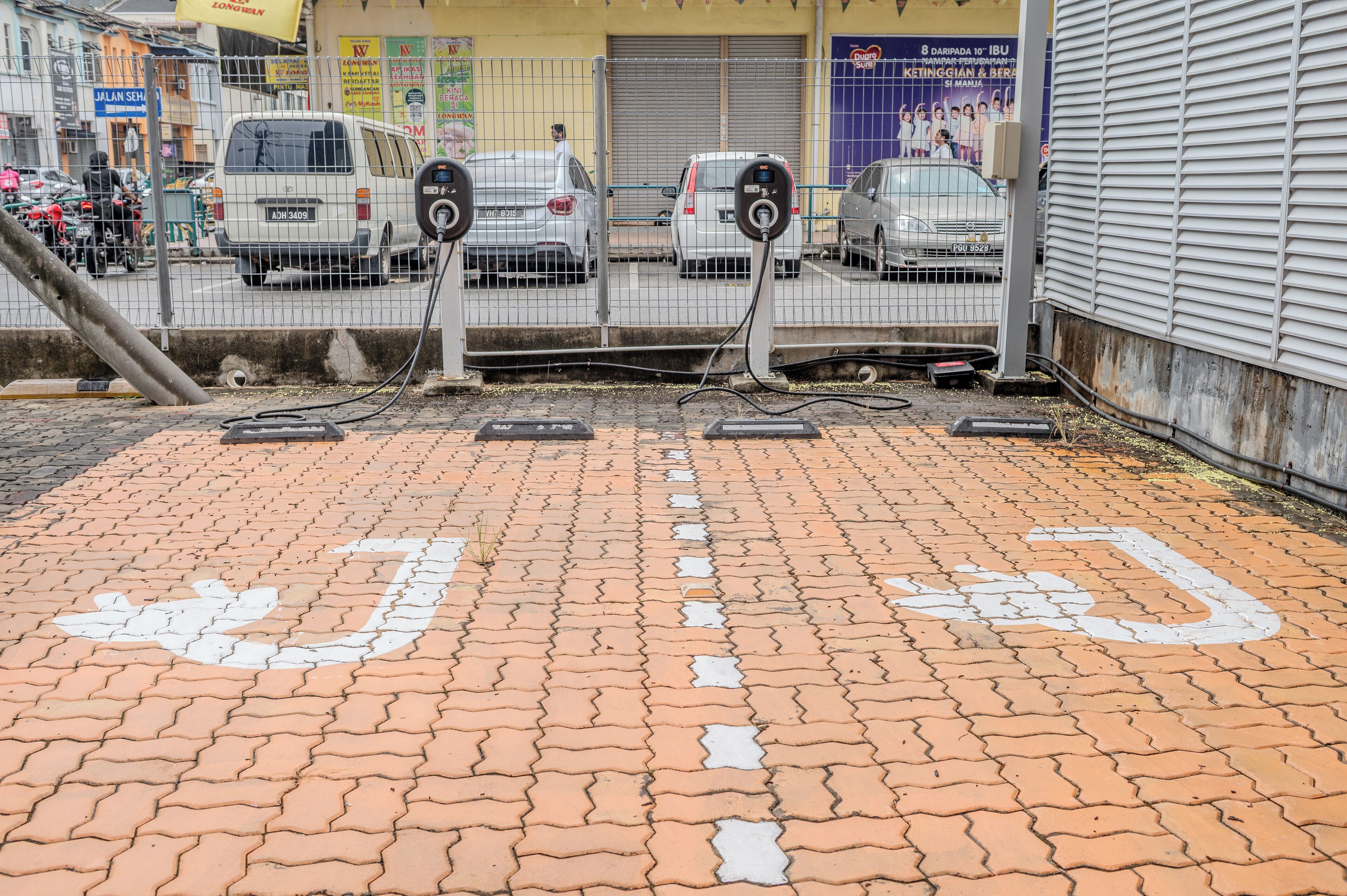 A parking area with electric vehicle charging stations and a paved walkway.
