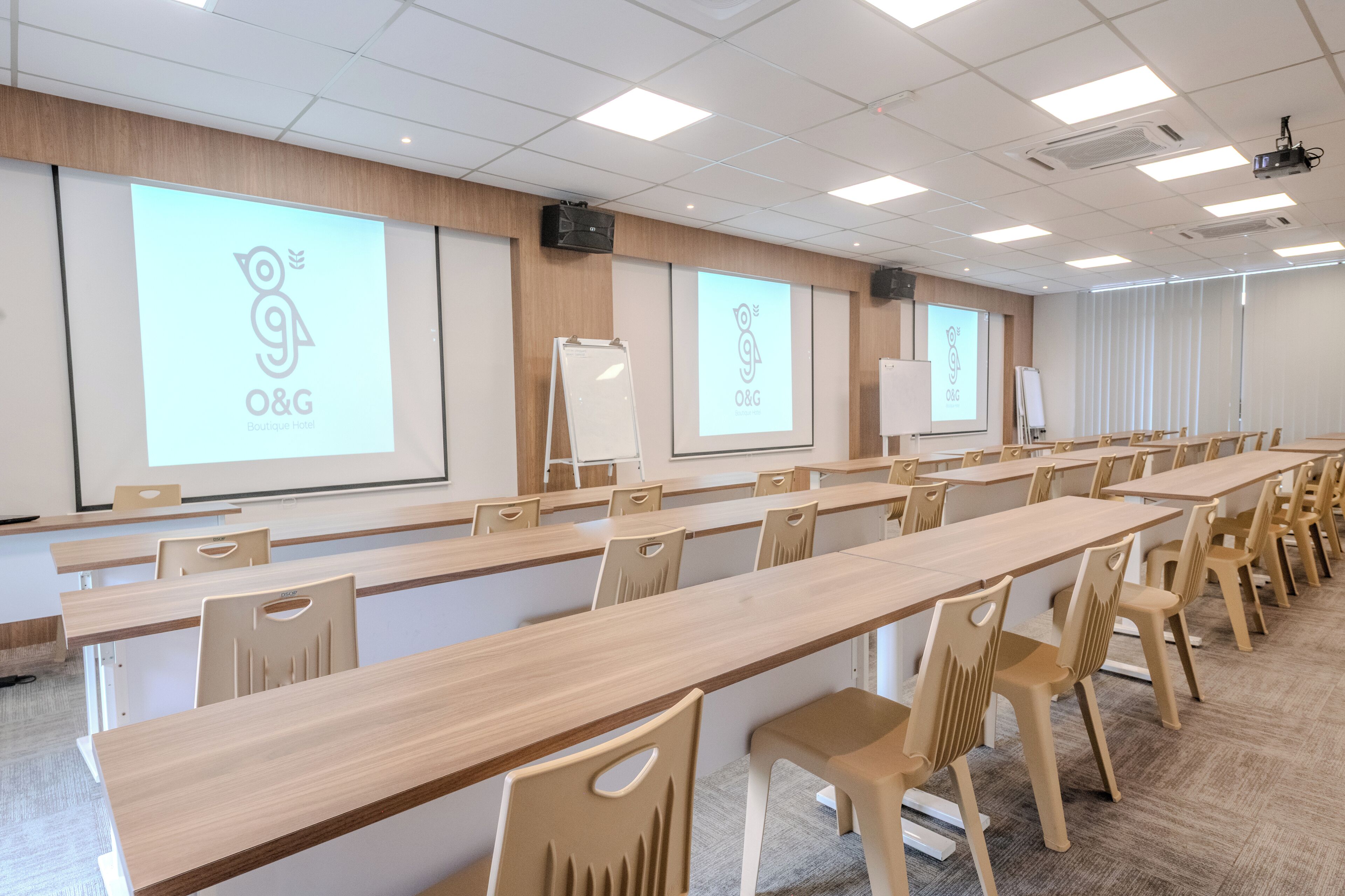 Une salle de conférence équipée de longues tables et de chaises, d’un tableau blanc et d’écrans de projection affichant le logo de l’entreprise.