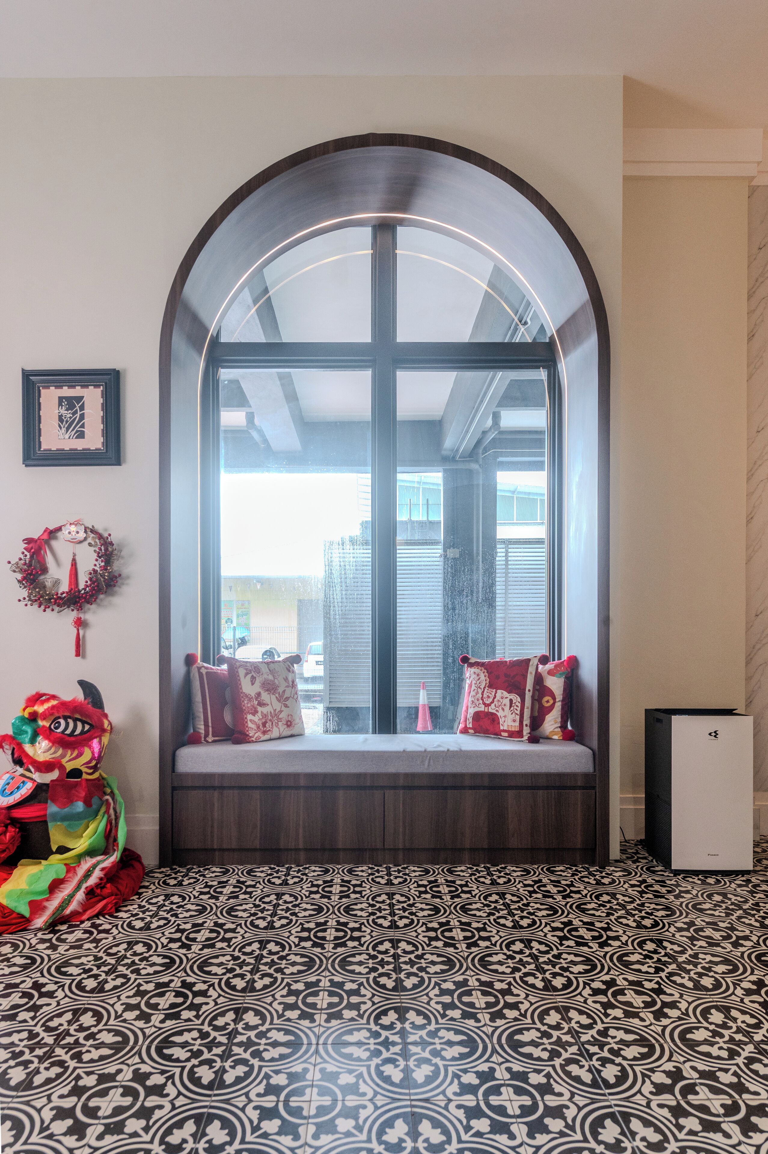 A room with a large arched window, a patterned floor, and a bench with pillows.