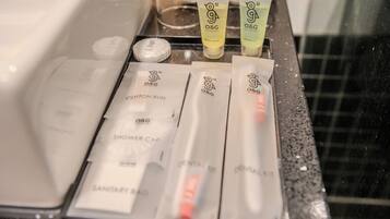 Artículos de aseo y productos de baño sobre una encimera en el baño de un hotel.