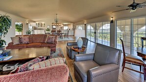 Ein geräumiges Wohnzimmer mit einer großen Eckcouch, einem Ledersessel und einem Couchtisch. Es gibt einen Essbereich mit Tisch und Stühlen, und im Hintergrund befindet sich eine Küche.