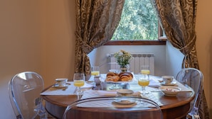 Una mesa de desayuno servida con cruasanes, jugo de naranja y un jarrón con flores.
